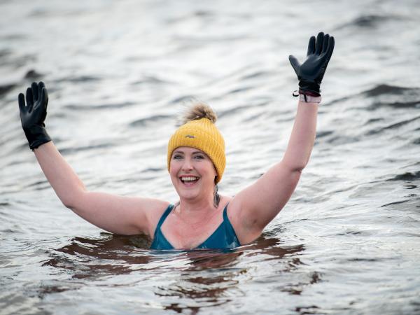 Karen stands in the water smiling with her arms in the air