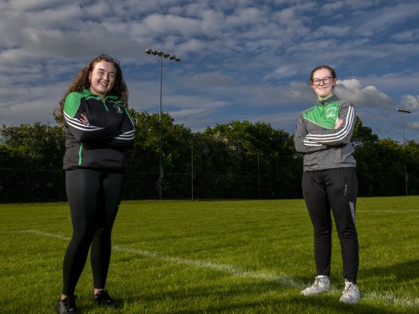 Kate Russell and Ciara Floyd stand on a soccer pitch with arms folded looking at the camera